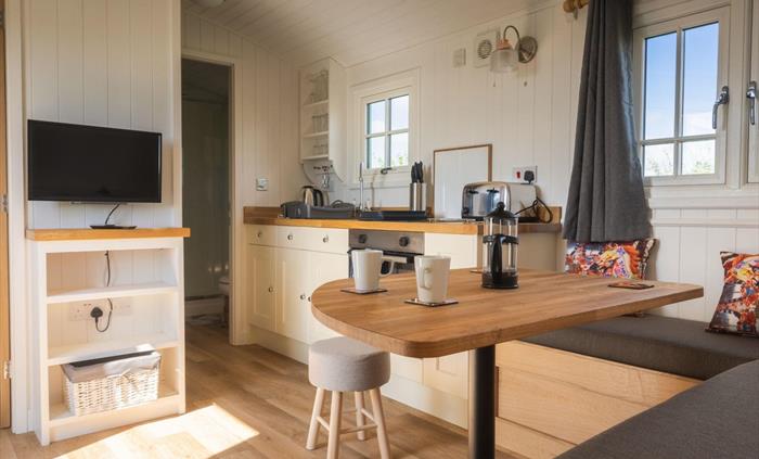 Dining table, bench seating and galley kitchen with fairground styling